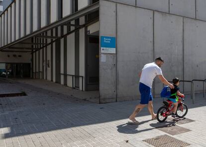 Un pare i el seu fill passegen davant d'una escola tancada al Poblenou. 