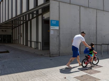 Un pare i el seu fill passegen davant d'una escola tancada al Poblenou. 