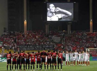 Los jugadores del Milan y el Sevilla guardan un minuto de silencio mientras en el videomarcador se ve una imagen de Puerta.