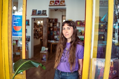 Sara Hernández, trabajadora de la librería 'Tres Hermanos Moriarty', posa junto al cartel en apoyo a Palestina en la puerta del establecimiento en Malasaña, Madrid.
