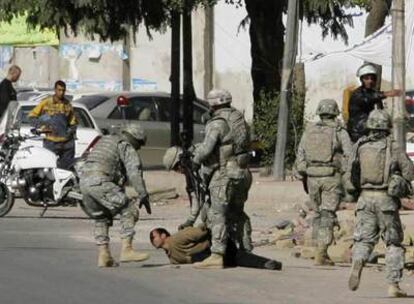 Soldados estadounidenses detienen a un iraquí el miércoles tras la explosión de una bomba en el centro de Bagdad.