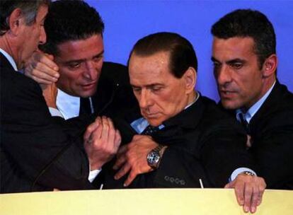 Berlusconi se desploma en el atril del Palacio de Congresos de Montecatini mientras su doctor y dos guardaespaldas tratan de sostenerle.