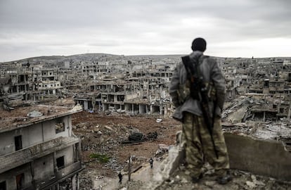 Um francotirador curdo observa do alto de um edifício a cidade destruída de Kobane, na fronteira com a Turquia. Em janeiro, os curdos recuperaram o controle da cidade.