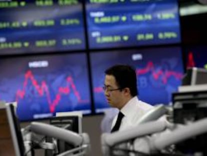 Un corredor de bolsa trabaja junto a una pantalla que muestra información bursátil en Seúl (Corea del Sur). EFE/Archivo