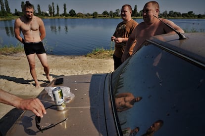 Un grupo de militares emplea el cap de un coche Lada como improvisado lugar de vestuario antes de regresar a sus posiciones tras darse un ba?o. 