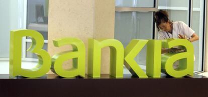 Una operaria limpia el logo de Bankia. +