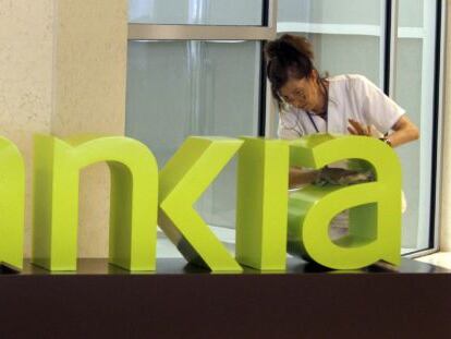 Una operaria limpia el logo de Bankia. +