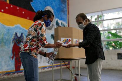 Una mujer se desinfecta las manos antes de votar en Caracas. Las normas del Consejo Nacional Electoral contemplan únicamente el uso de tapabocas y de gel antibacterial para electores y miembros de mesa.