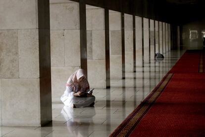 Una mujer lee el Corán en uno de los pasillos de la mezquita de Istiqlal, en Yakarta (Indonesia).
