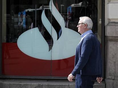 Un hombre pasando por delante de una oficina de Banco Santander