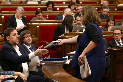La diputada de la CUP Eulàlia Reguant le regala el libro "L'hora dels voltors", de Josep Manel Busqueta, al vicepresidente Oriol Junqueras durante el Pleno de los Presupuestos.