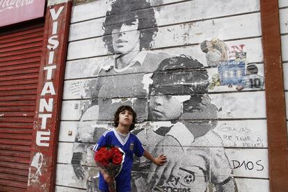 Hinchas de Argentinos Juniors, el equipo del barrio de La Paternal que fue cuna de Diego Maradona, realizaron una vigilia para recordar a su figura más legendaria. En esta foto, tomada el 28 de noviembre de 2020, un niño lleva rosas ante uno de los tantos murales que adornan el estadio donde el 20 de octubre de 1976 el astro debutó en la Primera Divisiónb. Maradona no había cumplido aún 16 años. “Me acuerdo que vinieron a verme mis viejos, mis hermanos y todos Los Cebollitas. No me lo olvido más”, contó años después Maradona sobre su debut.