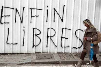 Una mujer camina ante una valla de Túnez capital en la que se lee una pintada en francés: "Al fin libres".
