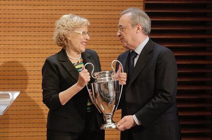 El presidente del Real Madrid, Florentino Pérez (d), y la alcaldesa de Madrid, Manuela Carmena sostienen el trofeo que acredita al equipo blanco como vencedor de la Liga de Campeones.