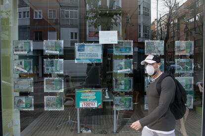 Un hombre pasa ante una inmobiliaria cerrada durante el estado de alarma, en Madrid.