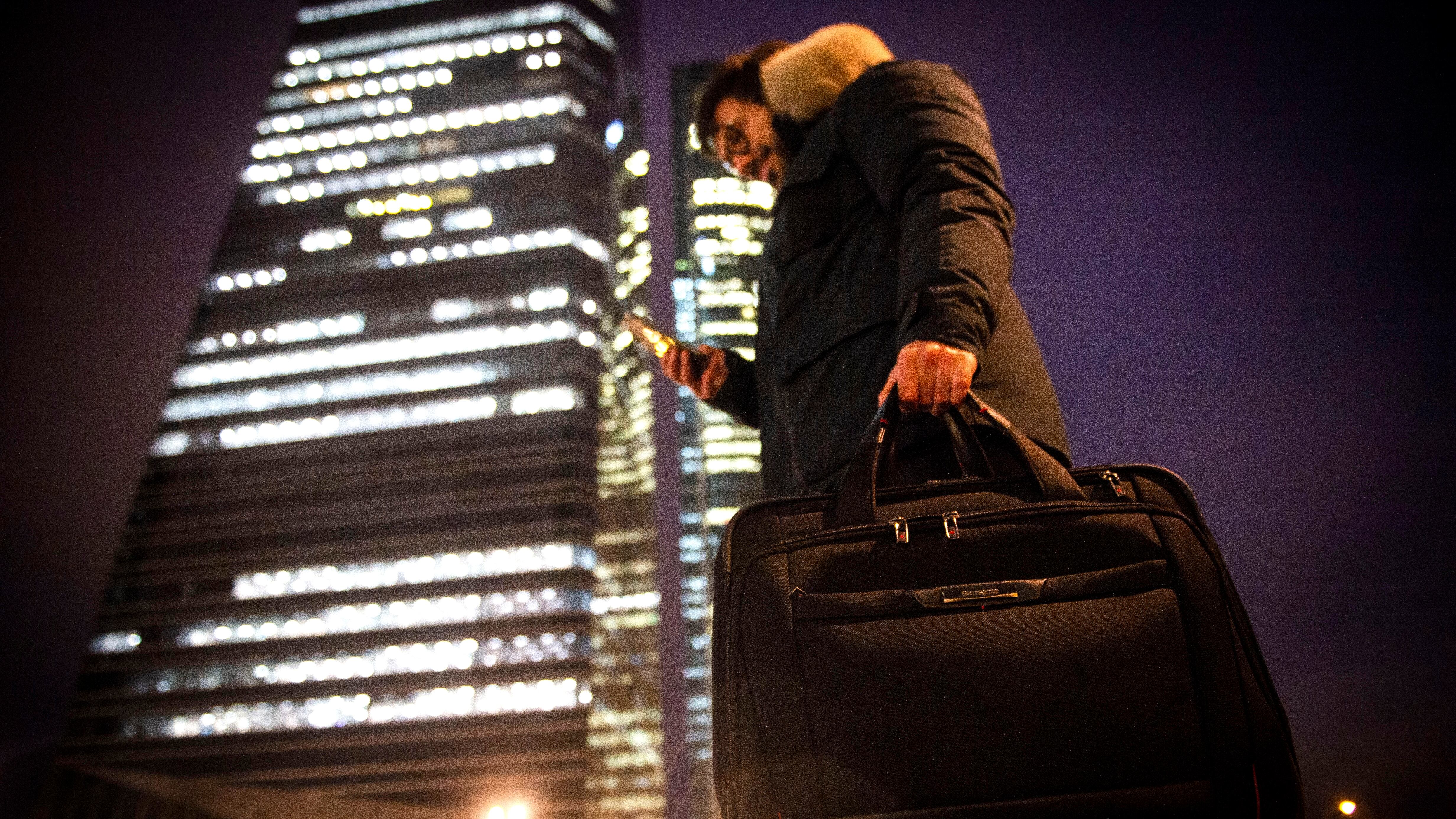 Un hombre mira su móvil frente a las cuatro torres de Madrid, en marzo de 2023.