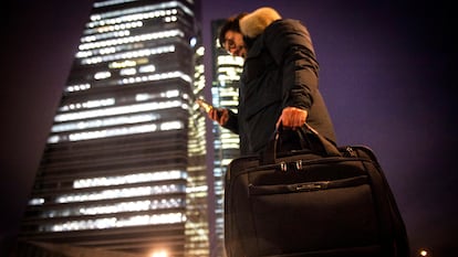 Un joven carga con su ordenador portátil en el distrito financiero de las cuatro torres, en Madrid.