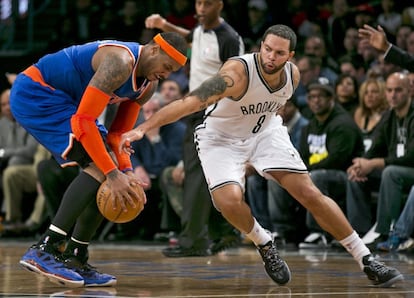 Deron Williams trata de robarle el balón a Carmelo Carmelo Anthony.