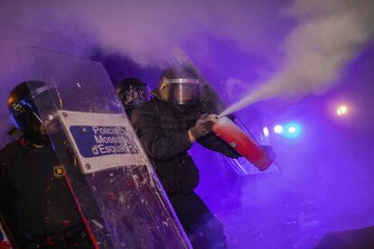 A policeman uses a fire extinguisher on a burning barricade during clashes with protestors in Barcelona.
