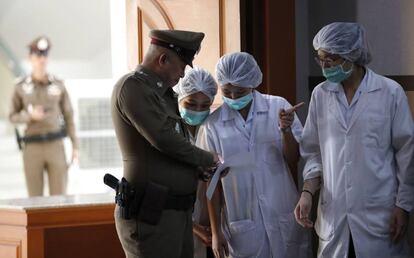 Personal del hospital tailandés y un oficial de policía a las puertas del Hospital Chiangrai Prachanukroh en la provincia de Chiang Rai.