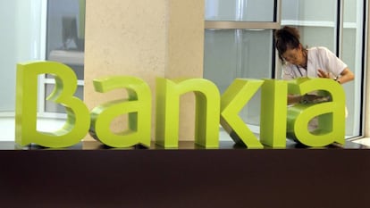 Una operaria limpia el logo de Bankia.