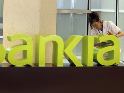 Una operaria limpia el logo de Bankia.