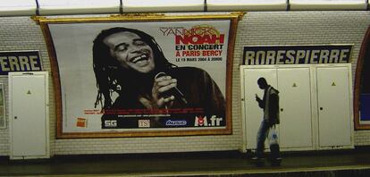 Un pasajero transita el and&eacute;n de la estaci&oacute;n parisina de Robespierre, en la comuna de Montreuil, mientras el extenista Yannick Noah parece mirarle desde el anuncio enmarcado de uno de sus conciertos.