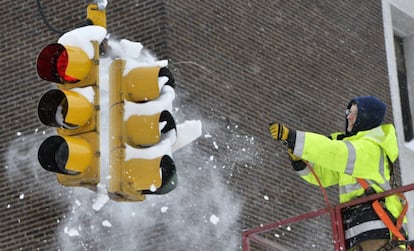 Un trabajador intenta quitar la nieve de un semáforo tras las grandes nevadas en Erie (Estados Unidos).