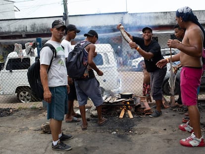 Grupo de venezuelanos assa peixe em churrasqueira improvisada, perto da estação de ônibus de Manaus