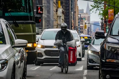 A food delivery worker rides through the a busy street in lower Manhattan