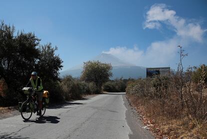 Las autoridades han pedido a la población no ascender al cráter del volcán, ante el riesgo de la emisión de fragmentos incadescentes. En la imagen, un hombre monta su bicicleta en el municipio de Xalitzintla, mientras el Popocatépetl expulsa una columna de vapor. 