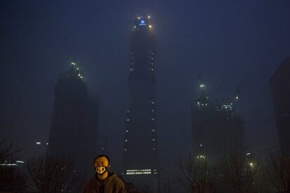 Un hombre con una mascarilla con diseño de esqueleto aparece entre la niebla tóxica de Pekín (China).