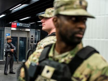 New York State Police officer and members of the New York State National Guard stand guard inside the entrance of subway station in New York City, U.S., March 7, 2024.