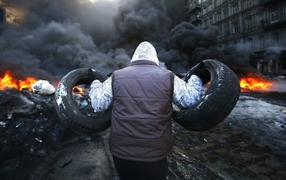 Un hombre lanza neumáticos a las hogueras durante los enfrentamientos con la policía ucraniana en Kiev, 23 de enero de 2014.