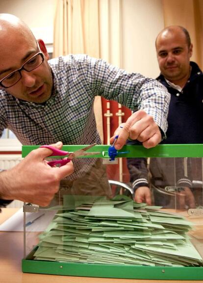 El presidente de una mesa corta el precinto de una urna antes del inicio del recuento de votos.