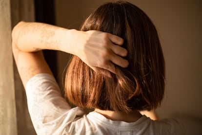 Rear view of a woman with bob haircut, holding her head.