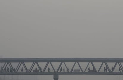 Transeuntes atreviesan un puente peatonal en Pekín (China), bajo una nebulosa de contaminación que cubre la capital. China ha emitido su primera alerta de contaminación del aire para la temporada de invierno.