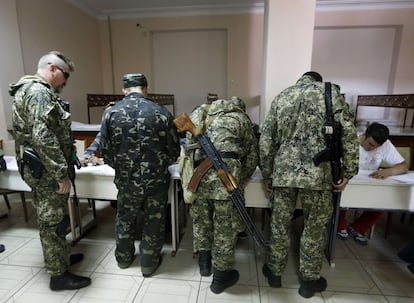 Milicianos armados pró-russos se cadastram antes de votar em um colégio eleitoral em Slaviansk.