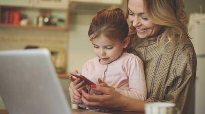 Una niña usa su 'smartphone' junto a su madre.