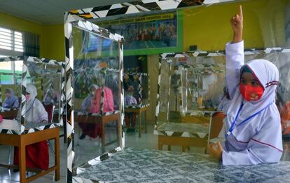 Estudiantes de primaria en una clase presencial utilizando pantallas plásticas para separar las mesas de forma individual, en Solok, provincia de Sumatra Occidental (Indonesia).