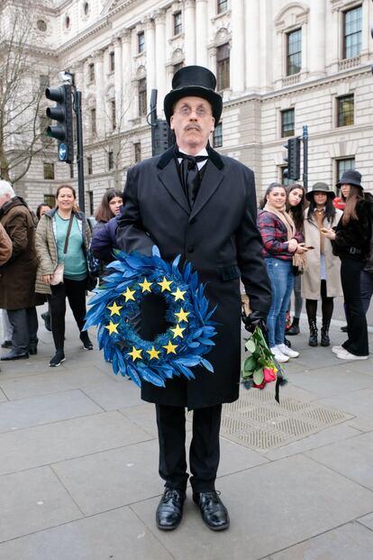 Un británico se disfraza de enterrador y coloca la bandera de la UE en una corona funeraria. 