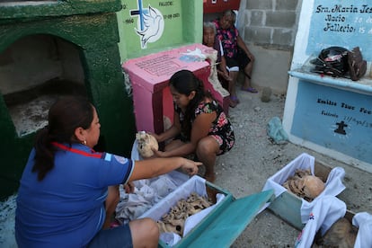 La limpieza de los restos empieza alrededor del 25 de octubre y concluye el 30, pues el 31 las familias se dedican a montar ofrendas en sus casas y en el cementerio. En la imagen, dos mujeres limpian huesos en el cementerio de Pomuch.