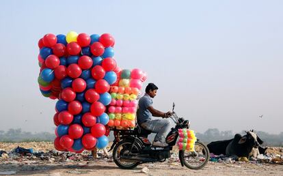 Un chico transporta globos de colores en su motocicleta en Delhi (India).