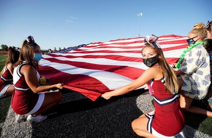 Las animadoras de los Herriman Mustangs sostienen una bandera de Estados Unidos antes del partido de fútbol americano contra los Davis Darts. Este es el primer partido de instituto desde que comenzó la pend emiaen Herriman (Utah).