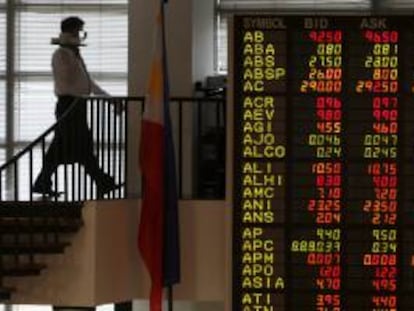 Un camarero camina junto a un panel con información bursátil en el parqué filipino en Makati, al sur de Manila, Filipinas. EFE/Archivo