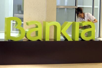 Una operaria limpia el logo de Bankia 