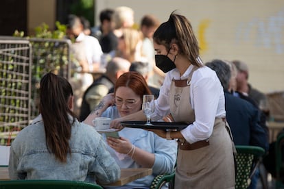 Una camarera atiende una terraza en el centro de Sevilla.