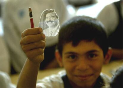 Un niño recorta una imagen de Sadam de un libro de texto, hoy en un colegio de Bagdad.