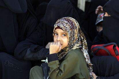 Una niña yemení se sienta entre mujeres vestidas con burqa esperando recibir alimentos tras el ayuno diario de Ramadán en Saná (Yemen).