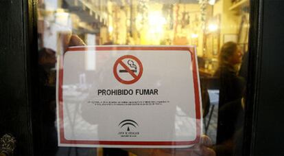 Un bar cuelga el cartel de prohibido fumar ayer, en el centro de Sevilla.